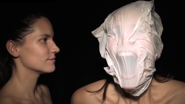 Eine Frau blickt auf eine andere Frau, deren Kopf in einer Plastiktüte steckt.