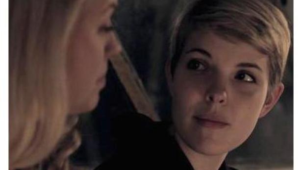 Eine Frau mit kurzen blonden Haaren schaut eine andere Frau an.