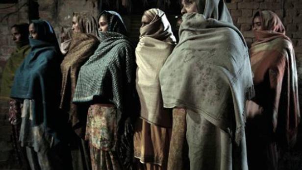 Eine Gruppe verschleierter Frauen steht vor einer Mauer.