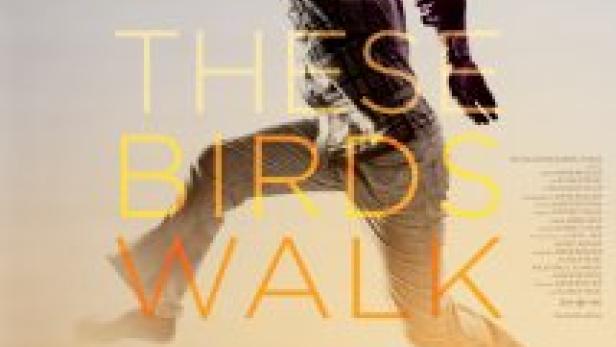 Ein Mann springt vor dem Hintergrund des Filmplakats „These Birds Walk“.