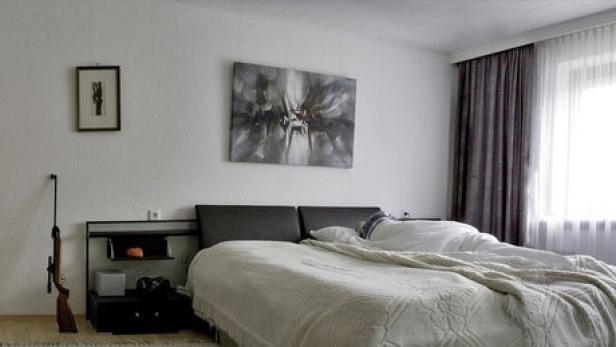 Ein Schlafzimmer mit einem Gewehr an der Wand neben dem Bett.