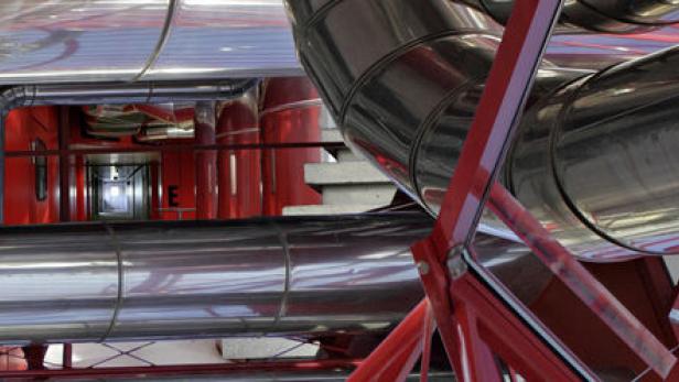 Ein komplexes System aus glänzenden Rohren und roter Stahlkonstruktion.