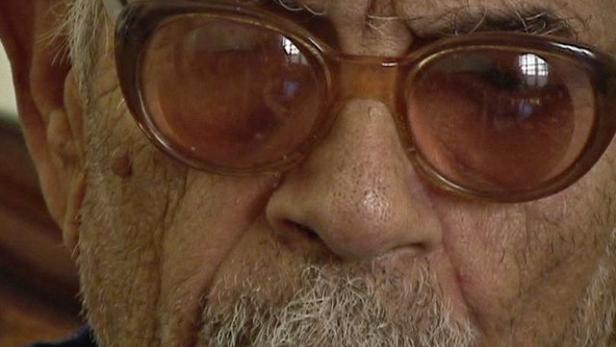 Nahaufnahme eines älteren Mannes mit Brille und grauem Bart.