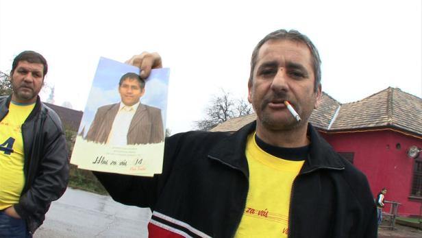 Ein Mann hält ein Foto eines anderen Mannes in der Hand und raucht eine Zigarette.