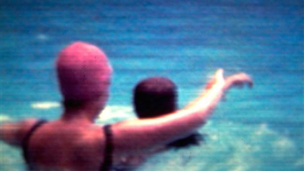 Zwei Personen schwimmen im blauen Wasser.