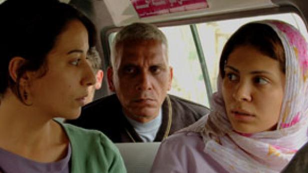 Drei Personen sitzen in einem Fahrzeug, zwei Frauen und ein Mann.