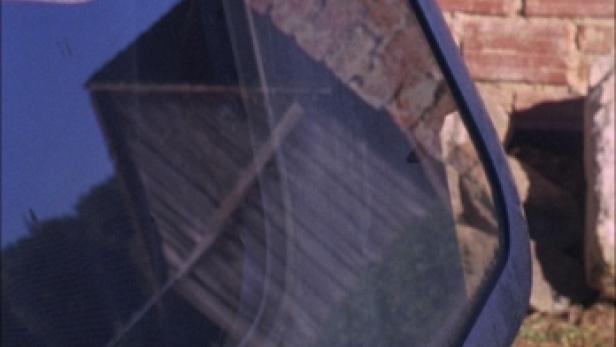 Die Spiegelung eines Gebäudes in einer Autoscheibe.