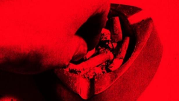 Eine Hand drückt eine Zigarette in einem Aschenbecher aus.