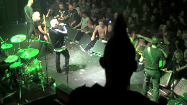 Eine Punkband spielt vor einem begeisterten Publikum in einem Konzertsaal.