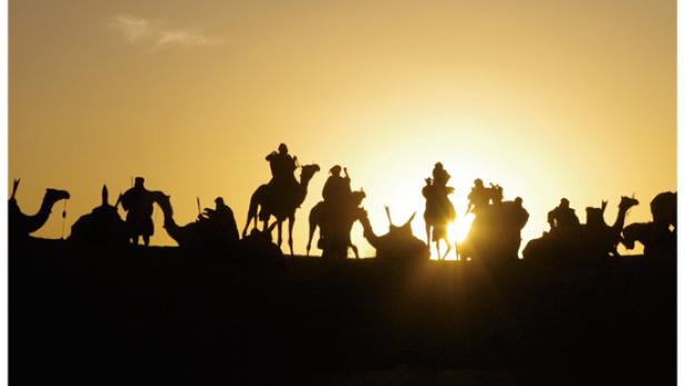 Das Filmplakat zu „Woodstock in Timbuktu“ zeigt eine Karawane im Sonnenuntergang.