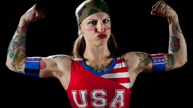 Eine tätowierte Frau im USA-Trikot spannt ihre Muskeln an.