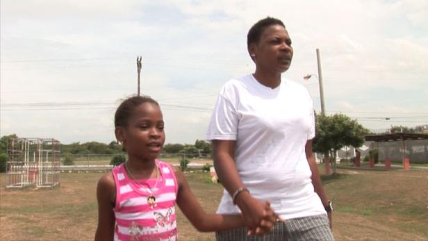 Eine Frau hält die Hand eines kleinen Mädchens in einem Park.