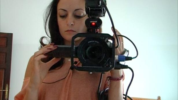 Eine Frau filmt sich selbst mit einer professionellen Videokamera.