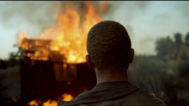 Ein Mann blickt auf ein brennendes Gebäude.