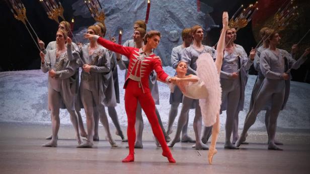 Eine Ballettaufführung mit einer Ballerina in Weiß und einem Tänzer in Rot im Rampenlicht.