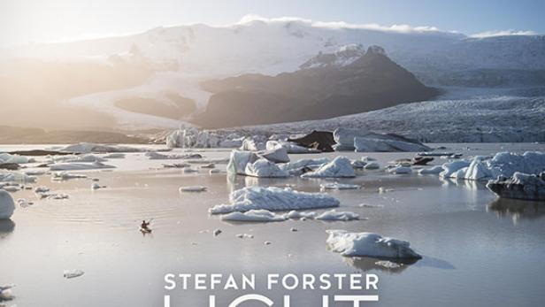 Das Filmplakat für „Light Hunter“ zeigt eine isländische Gletscherlandschaft mit Eisbergen und einem Kajakfahrer.