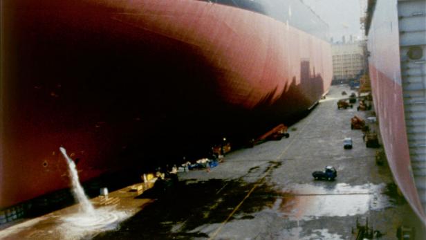 Ein großes Schiff im Trockendock, wo Wasser aus einer Öffnung abgelassen wird.