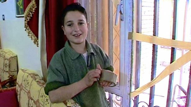 Ein lächelnder Junge steht vor einer mit Klebeband gesicherten Tür.