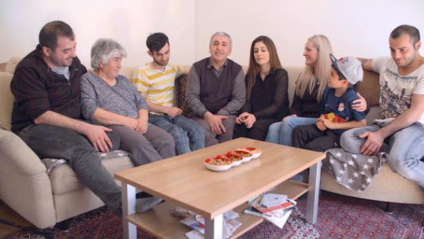 Eine Familie sitzt zusammen auf einem Sofa in einem Wohnzimmer.