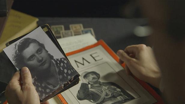 Eine Person betrachtet alte Fotos und eine Zeitschrift mit einem Porträt.