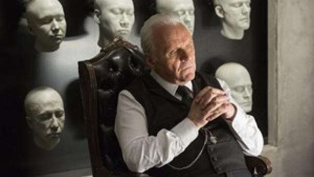 Anthony Hopkins in Westworld vor einer Wand mit Gesichtsabgüssen.