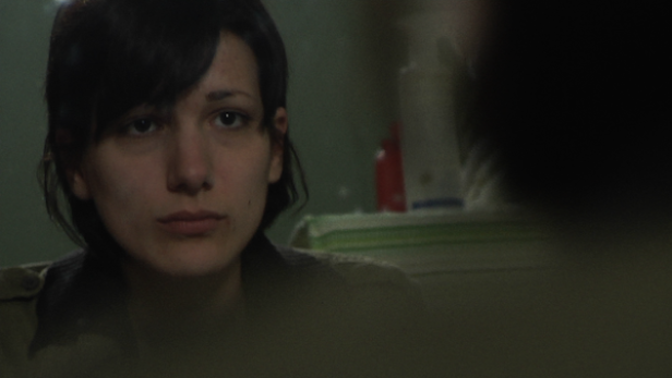 Eine Frau mit dunklen Haaren schaut aufmerksam in Richtung des Betrachters.