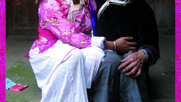 Zwei Mosuo-Frauen in traditioneller Kleidung posieren für ein Foto.