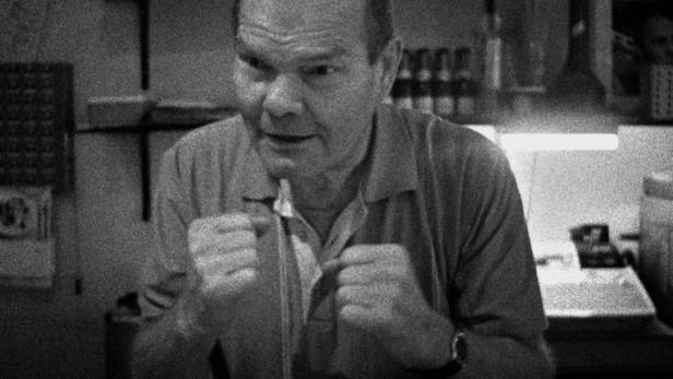 Ein Mann in Schwarzweißaufnahme schließt seine Jacke.