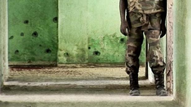 Ein Soldat steht vor einer Wand mit Einschusslöchern, Plakat für den Film „Mogadishu Soldier“.