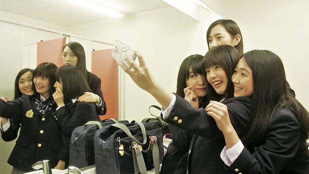 Eine Gruppe japanischer Schülerinnen macht ein Selfie in einem Badezimmer.