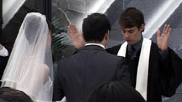 Ein Paar steht bei seiner Hochzeit vor einem Priester.