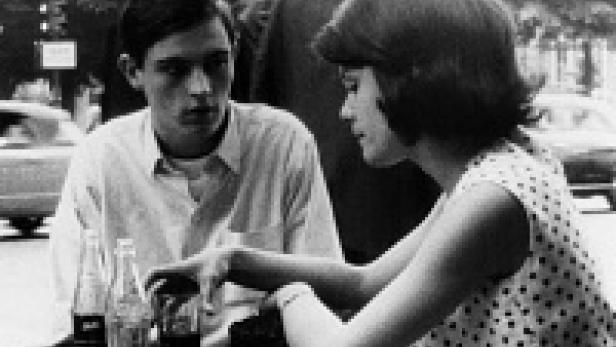 Ein junges Paar sitzt an einem Tisch im Freien und unterhält sich.