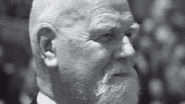 Ein älterer Mann mit Bart und Anzug blickt nach rechts.