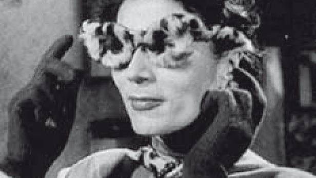 Eine Frau mit Handschuhen und einer ungewöhnlichen Brille posiert.