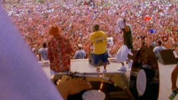 Eine Band tritt vor einer riesigen Menschenmenge im Freien auf.