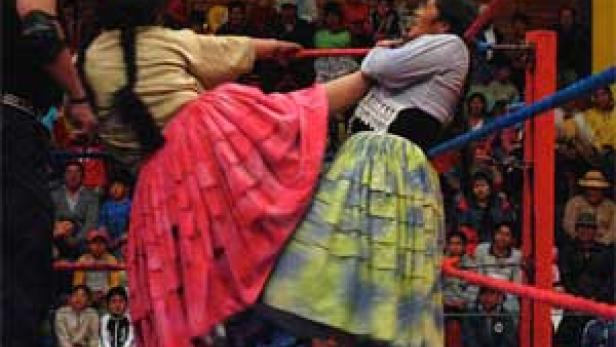 Zwei cholita-Wrestlerinnen kämpfen in traditioneller Kleidung in einem Ring.
