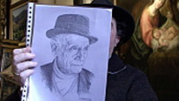 Eine Person hält eine Zeichnung eines älteren Mannes mit Hut vor ihr Gesicht.