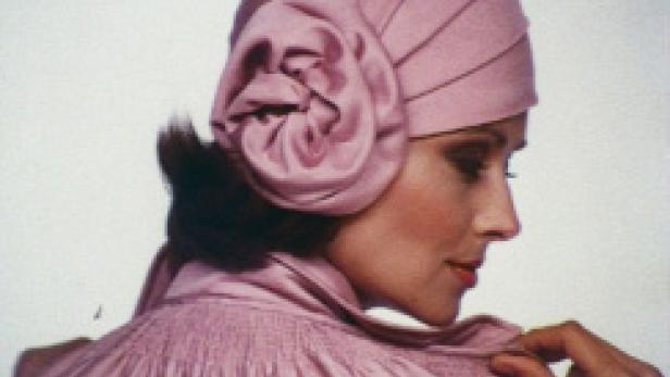 Eine Frau mit einem rosa Turban mit einer großen Stoffblume an der Seite.