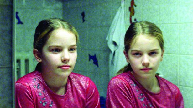 Ein junges Mädchen steht vor einem Spiegel im Badezimmer.