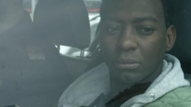 Ein Mann sitzt in einem Auto, möglicherweise in Polizeigewahrsam.