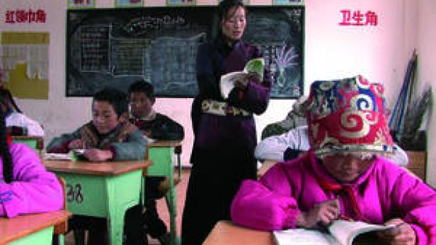 Eine Lehrerin steht vor einer Klasse von Schülern in einem Klassenzimmer.