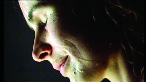 Nahaufnahme einer Frau mit geschlossenen Augen und Tränen im Gesicht.