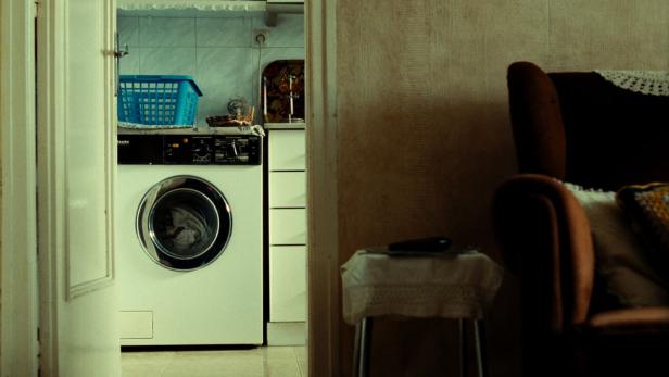 Blick durch eine Tür auf eine Waschmaschine und einen Sessel.