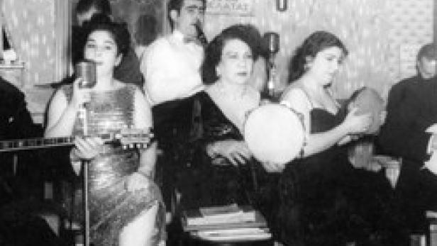 Eine Musikgruppe spielt in einem kleinen Raum mit Mikrofonen und traditionellen Instrumenten.