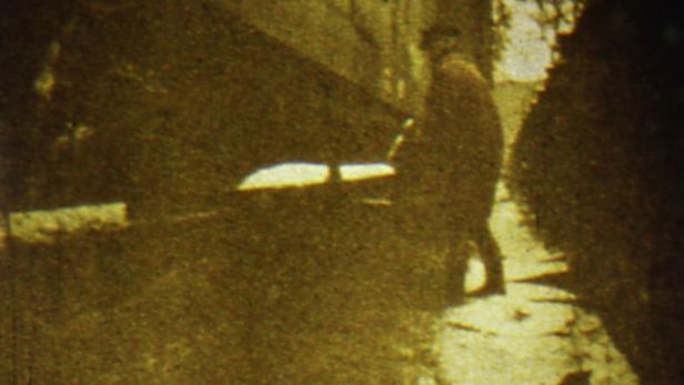 Eine Person geht eine Straße entlang, die von Gebäuden gesäumt ist.