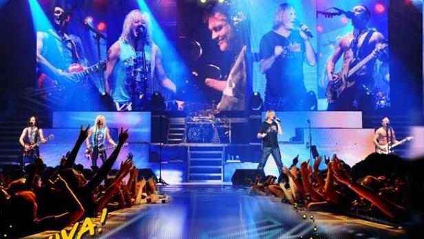 Die Band Def Leppard tritt vor jubelnden Fans auf einer Bühne auf, beworben mit „Viva! Hysteria“.