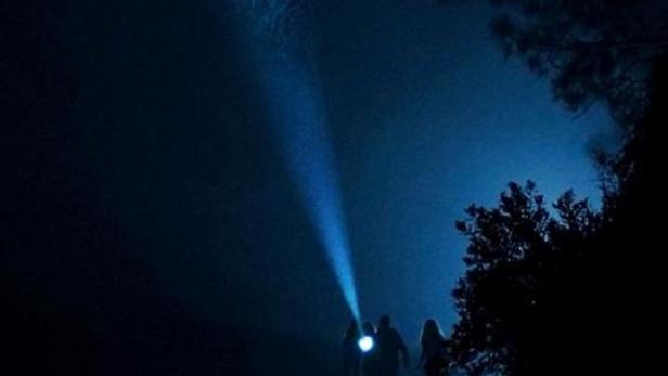 Das Filmplakat für „Sir-Ayet“ zeigt eine Gruppe von Personen im Wald, die in den Nachthimmel leuchten.