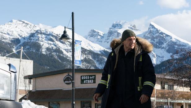 Liam Neeson in Winterkleidung vor einer verschneiten Bergkulisse.
