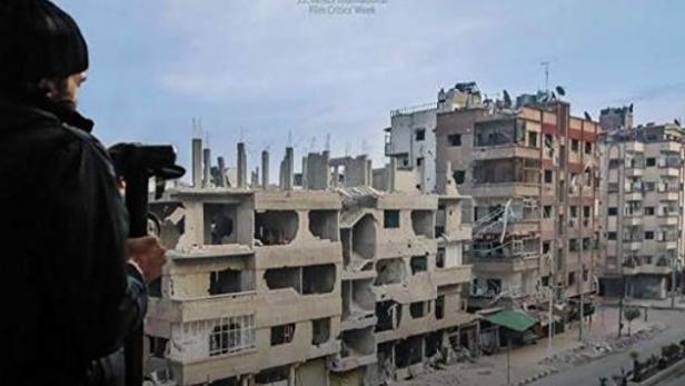 Ein Mann filmt zerstörte Gebäude im Filmposter für „Still Recording“.