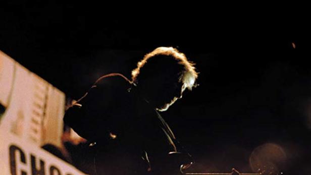 Das Filmplakat für „Roger Waters: Us + Them“ zeigt den Musiker mit Gitarre auf der Bühne.